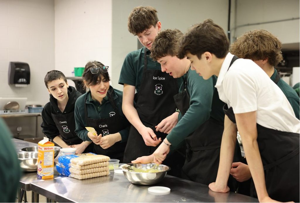 students standing over desk